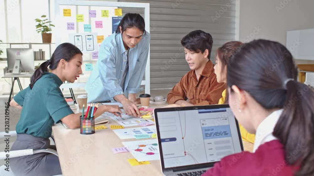 Young Asian business creative team work together, mobile application software design project. Brainstorm meeting, internet technology, office coworker teamwork concept. 4K tilt down forward dolly shot