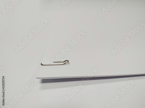 Close up of paper clip holding a blank paper sheet on white background.