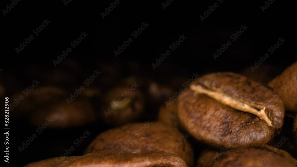 Macro shot of roasted Coffee beans on black surface. Full background of coffee beans. Aroma of coffee beans. Camera Truck from left to right. Macro shot of roasted Coffee beans on black surface. Full background of coffee beans. Aroma of coffee beans. Camera Truck from left to right.