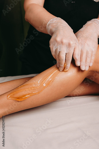 Sugaring procedure on legs done by a spa specialist during a procedure at the salon photo