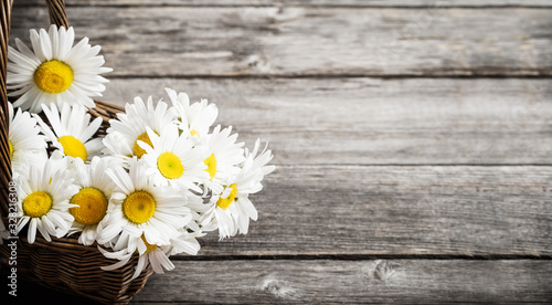 daisies in basket on old wooden background