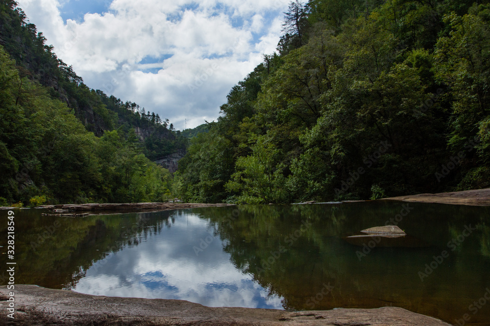 A calm pool of water under a summer sky in the valley of Tullulah Gorge.