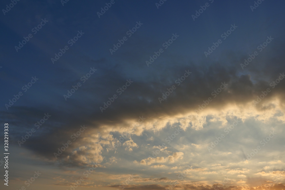 Dark and gold color curved cloud with sunbeam on beautiful blue sky at sunrise , Fluffy clouds formations at tropical zone	