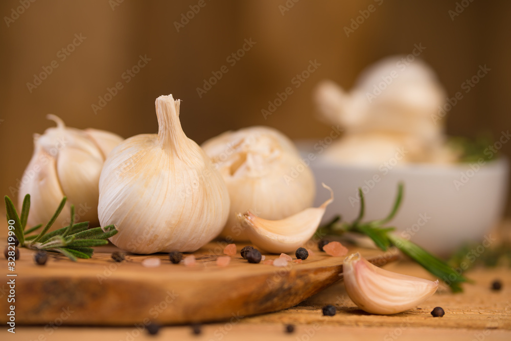 Spicy fresh garlic with rosemary and thyme and black pepper. Culinary splash, on a wooden background. Spicy fresh garlic with rosemary and thyme and black pepper. Culinary splash, on a wooden background.