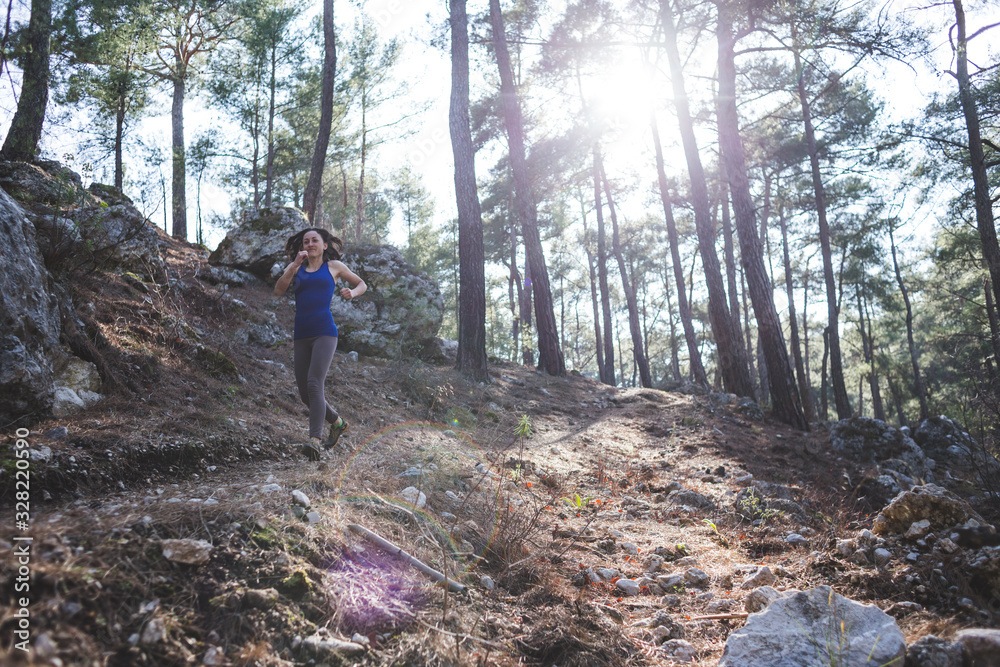 A woman runs along a mountain trail.
