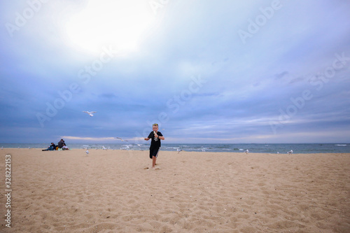 Young boy eating ice cream on the beach surrounded by seagulls 