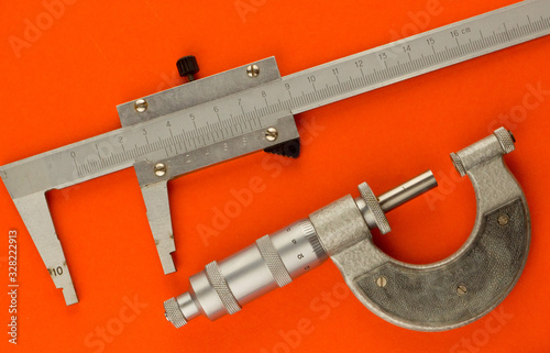 top view of a vernier caliper and micrometer on a bright orange background. Measuring tool. Accuracy of measurements