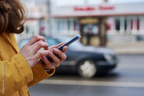 Woman using smartphone in the city outdoor, close up. Female hands typing message on mobile phone