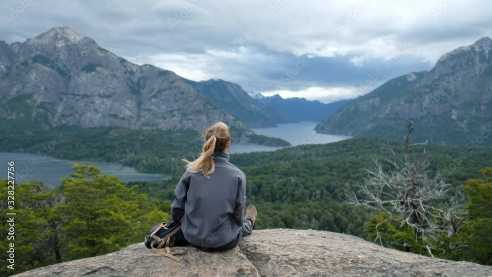 Young woman hiker sits on the rock and enjoys the windy valley with great view. Argentina, Patagonia Young woman hiker sits on the rock and enjoys the windy valley with great view. Argentina, Patagonia