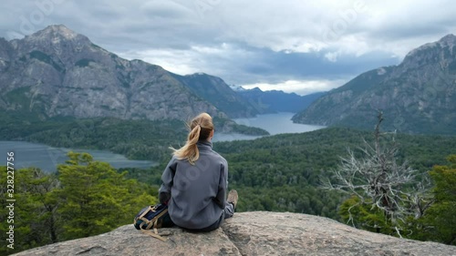 Young woman hiker sits on the rock and enjoys the windy valley with great view. Argentina, Patagonia