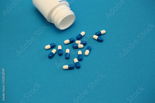 pills and bottle on blue background top view