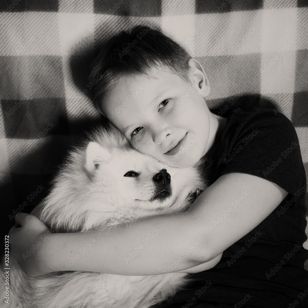 Boy is hugging a white dog with love Boy is hugging a white dog with love