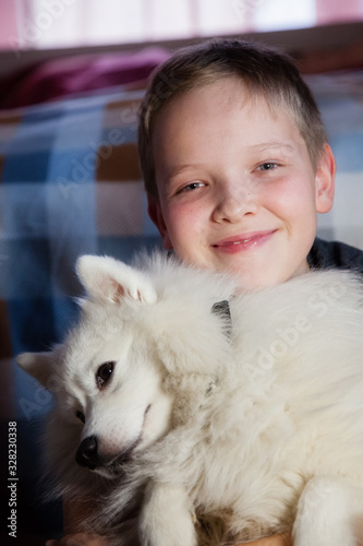 Fototapeta Naklejka Na Ścianę i Meble -  Boy is hugging a white dog with love