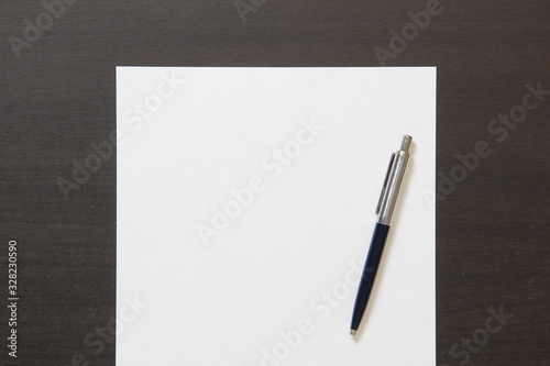 Template of white paper with pen on dark wenge color wooden background.
