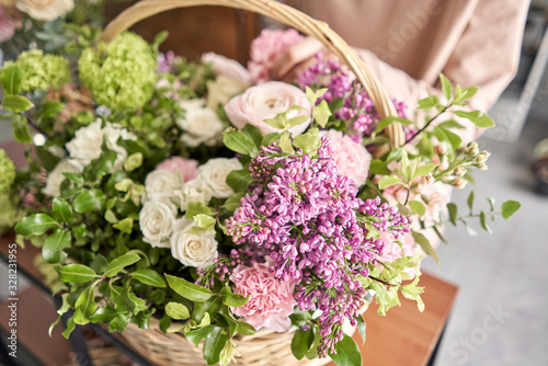 Floral shop concept . Florist woman creates flower arrangement in a wicker basket. Beautiful bouquet of mixed flowers. Handsome fresh bunch. Flowers delivery.