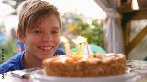 Happy child blows out candles on a birthday cake. Close up. slow motion.