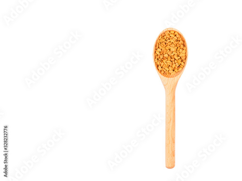 Spice fenugreek in wooden spoon isolated on white