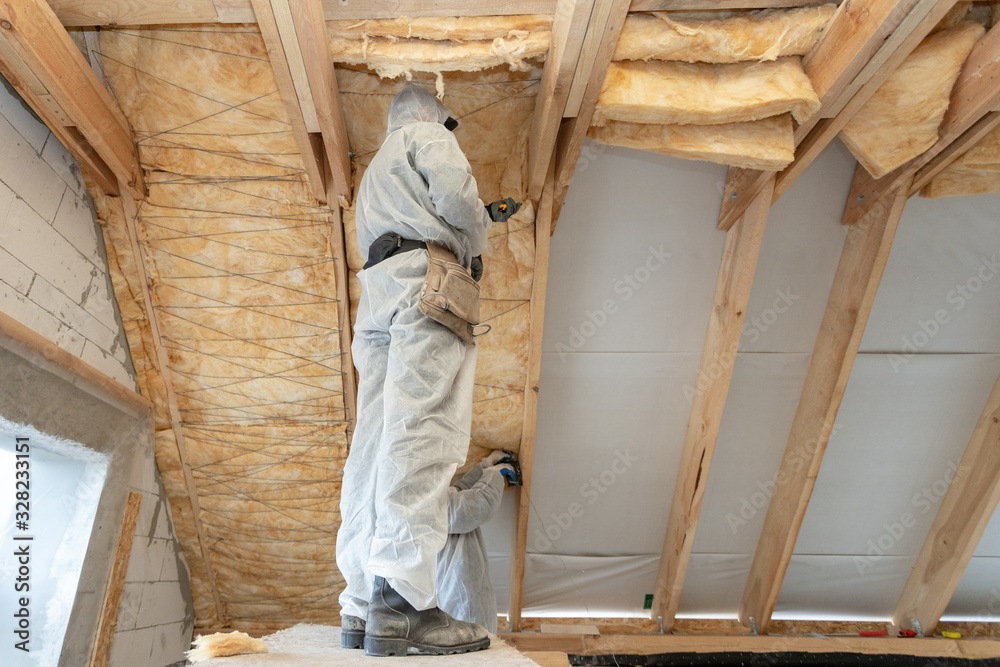 Foreman in overalls working with rockwool insulation material Foreman in overalls working with rockwool insulation material