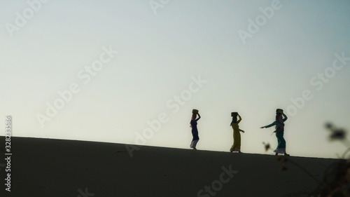 Fototapeta Naklejka Na Ścianę i Meble -  Beautiful photo of Cham's girls on the way back home on Nam Cuong sandy dune in dawn, Phan Rang, Ninh Thuan province, Vietnam
