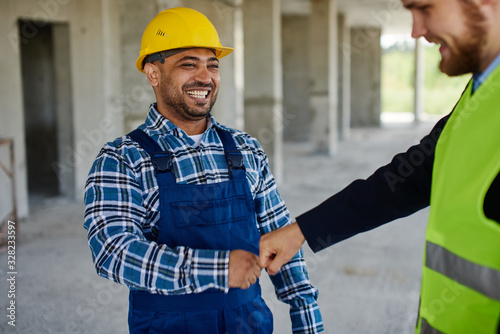 Two engineers discuss work related questions together, both smile at look at each other.