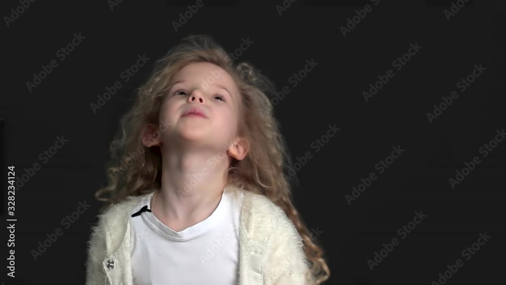 Little girl with blond curly hair, white shirt and white knitted jacket Little girl with blond curly hair, white shirt and white knitted jacket