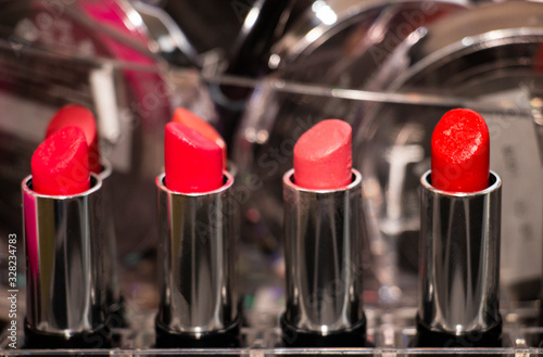 four red lipsticks in a row on a shiny background