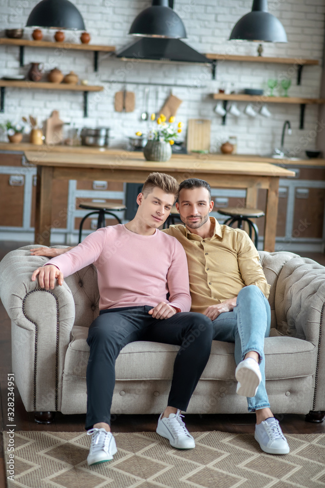 Two young men sitting on the sofa feeling relaxed Two young men sitting on the sofa feeling relaxed