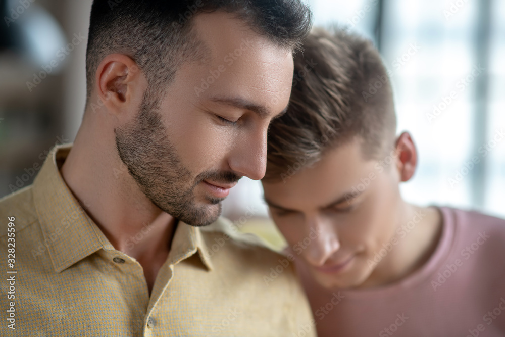 Two men standing next to each other feeling in love