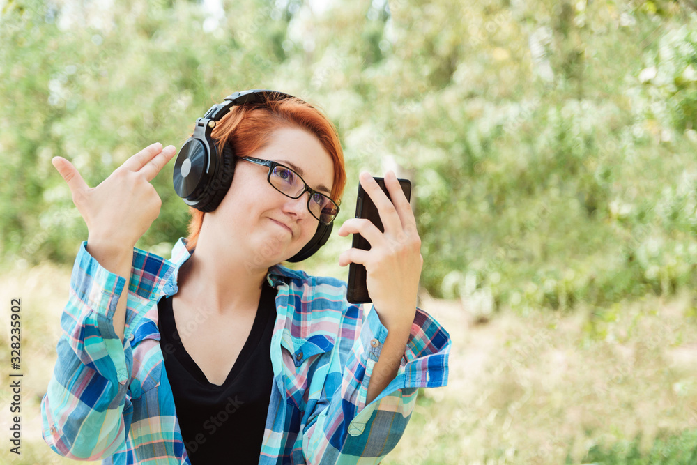 Cute ginger girl in glasses and headphones with phone. Failing or regret concept. Social media post. Cute ginger girl in glasses and headphones with phone. Failing or regret concept. Social media post.