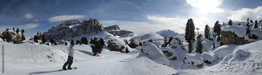 Obraz premium A girl riding snowboard in front of the Sella Group mountains. Dolomite Alps (Sella Ronda). Italy.