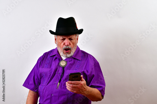 Old man is horrified by what he sees on his wireless phone. © Joe