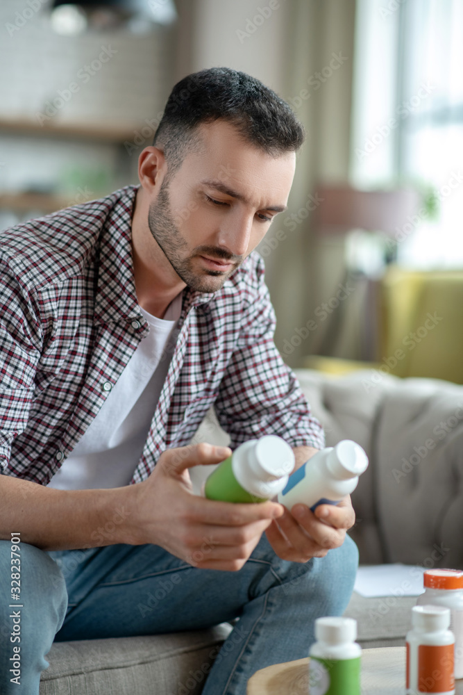 Young man in a checkered shirt choosing supplements Young man in a checkered shirt choosing supplements