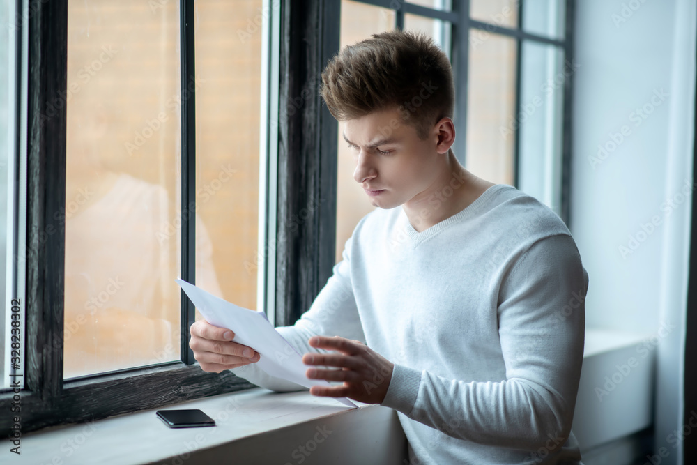 Young man in a white tshirt scrutinizing test results