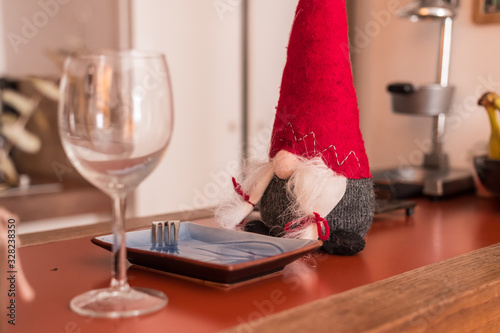 Fotografia Christmas female elf sitting on a table ready to have dinner and wine