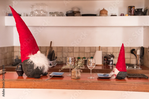 Fotografia Christmas elves sitting on a table ready to have dinner and wine