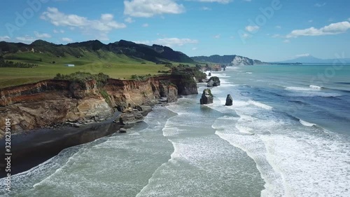 Aerial, drone shot, flying over the ocean, waves crashing into the cliffs, 4K, at the Three Sisters in New Zealand