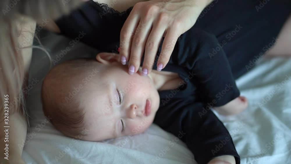 the mother stroking the head of a sleeping baby the mother stroking the head of a sleeping baby