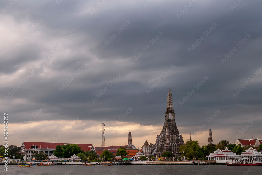 The famous Buddhist temple Wat Arun at sunset against a dramatic sky, Bangkok, Thailand