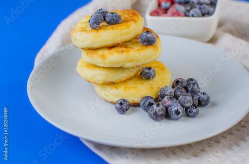 Pancakes with strawberries, raspberries, blueberries on a blue background.