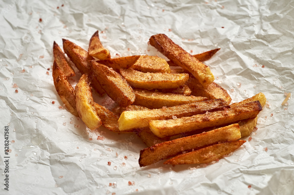 Tasty homemade potato french fries on white paper background Tasty homemade potato french fries on white paper background