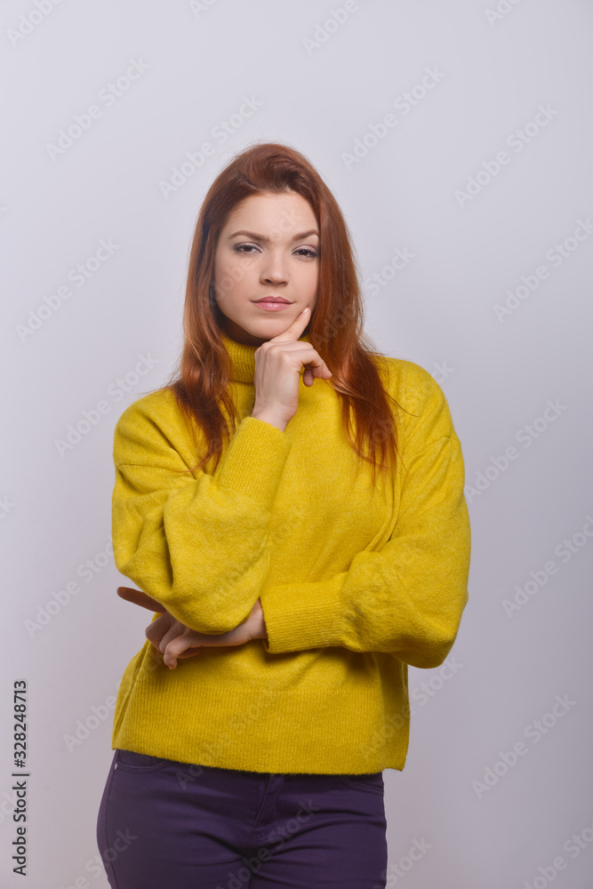 Confident young woman with finger on chin. Portrait of serious young woman standing with hand on chin and looking at camera. Confidence concept Confident young woman with finger on chin. Portrait of serious young woman standing with hand on chin and looking at camera. Confidence concept