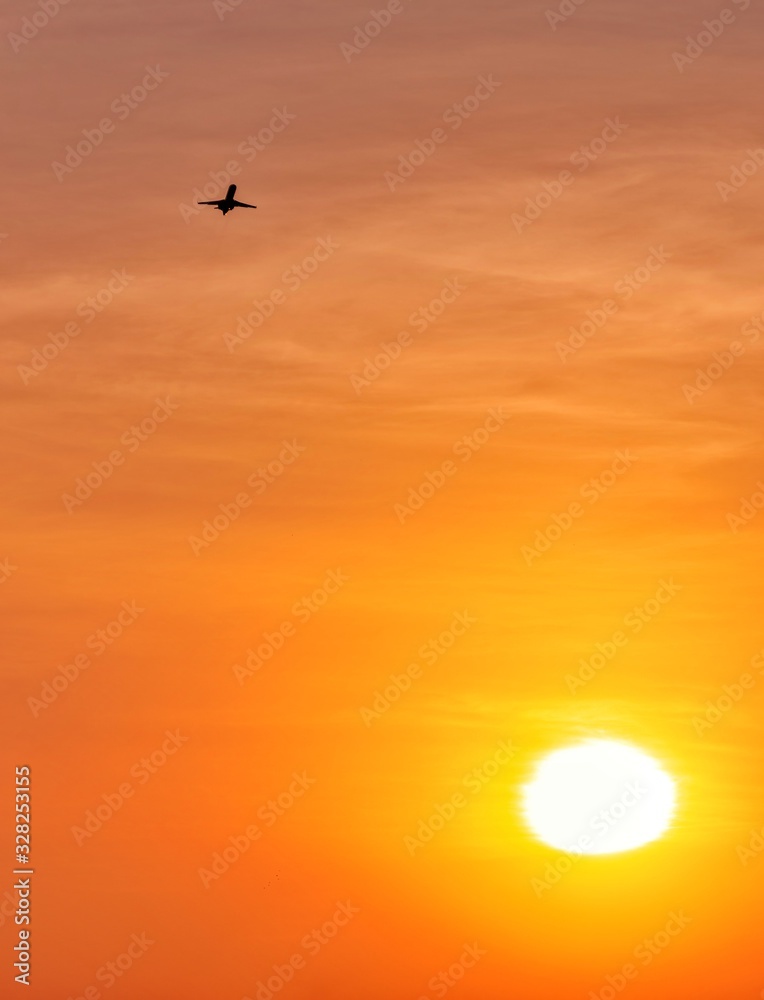 Airplane taking off against the sun during golden hour.