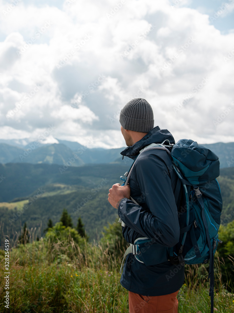 Man with backpack standing and enjoying the scenic view of mountains Man with backpack standing and enjoying the scenic view of mountains