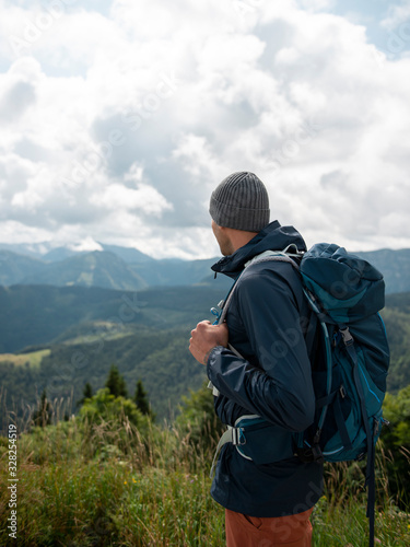 Man with backpack standing and enjoying the scenic view of mountains