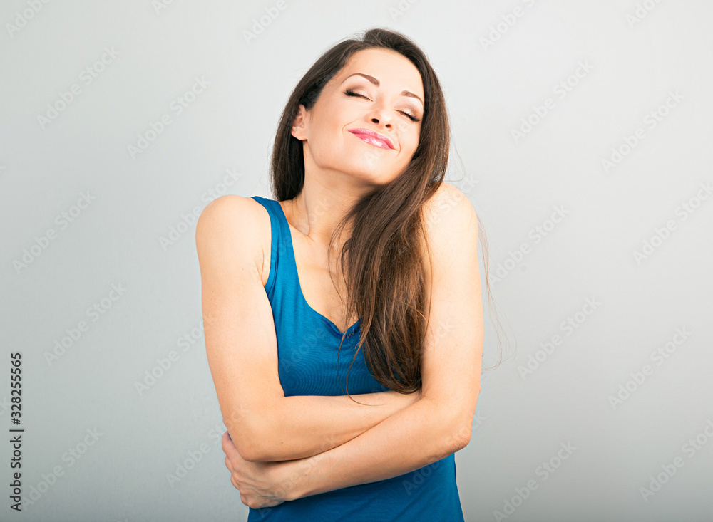 Happy sporty woman hugging herself with natural emotional enjoying face on blue background. Love concept Happy sporty woman hugging herself with natural emotional enjoying face on blue background. Love concept