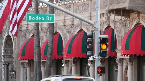 World famous Rodeo Drive Street Road Sign in Beverly Hills against American Unated States flag. Los Angeles, California, USA. Rich wealthy life consumerism, Luxury brands, high-class stores concept
