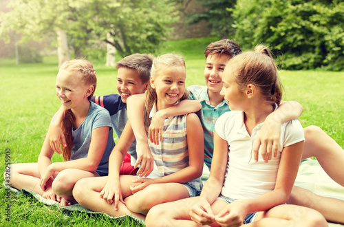 friendship, childhood, leisure and people concept - group of happy kids or friends sitting on grass in summer park © Syda Productions