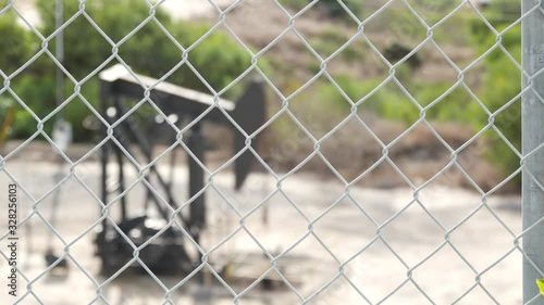 Industrial urban landscape. La Brea Inglewood in Los Angeles. Well pump jack operating behind the fence. Drilling rig extract crude oil. Oil mining machine with working piston. Oil and gas industry.