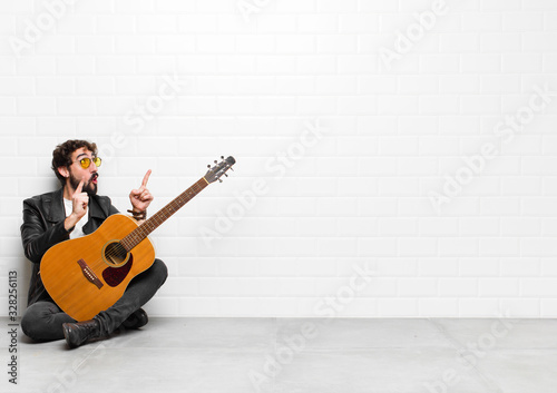 Quadro su tela young musician man feeling awed and open mouthed pointing upwards with a shocked