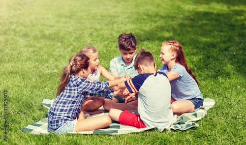summer holidays, friendship, childhood, leisure and people concept - group of happy pre-teen kids putting hands together in park © Syda Productions